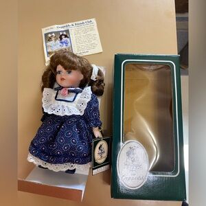 Geppeddo 9” Porcelain doll.  Blue eyes and brown hair in pigtails.  Blue dress.